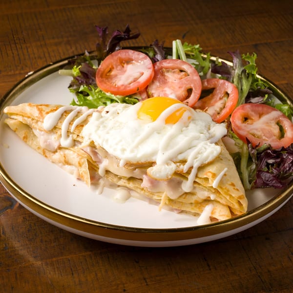 Savory crepe with ham, cheese, and a fried egg, served with a side salad at L'ORANGE CAFE.